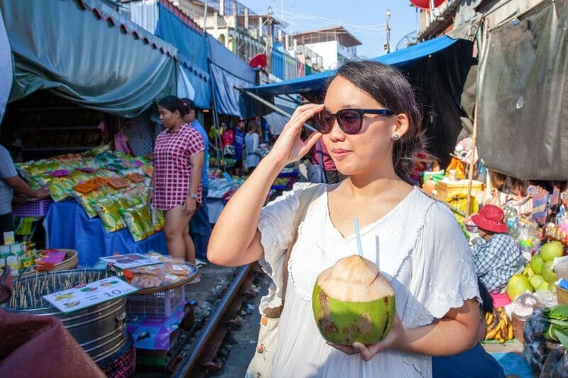 beber jugo de coco en mercado del tren bangkok